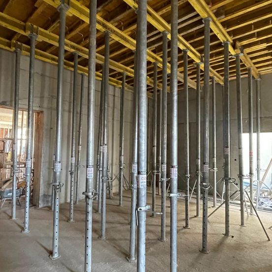 Ein Innenbaustelle mit Metallstangen und einem Arbeiter, der an Stapeln von Lagerkisten vorbeigeht.