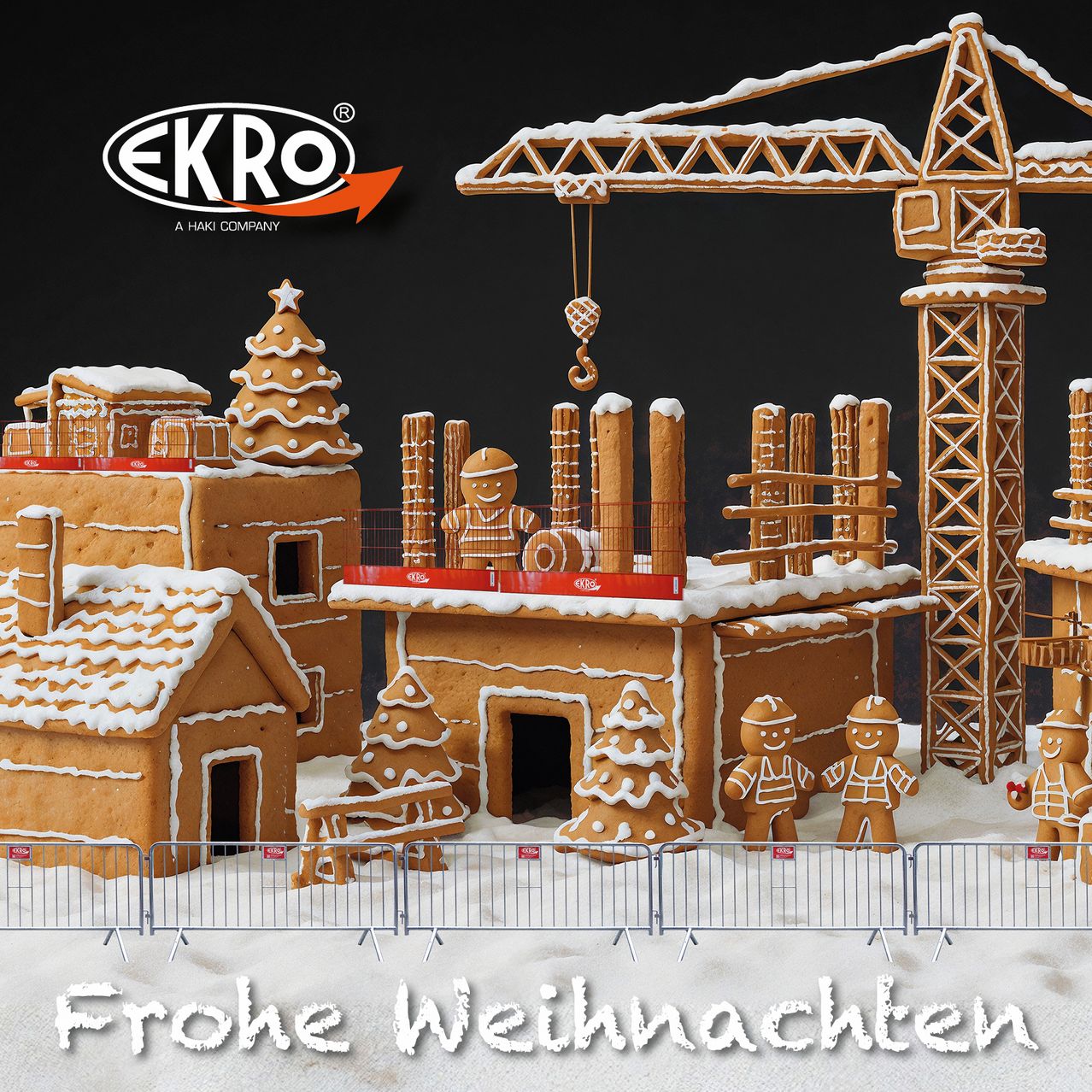 Eine Lebkuchendorfszene mit einer Baustelle, einem Kran und Lebkuchenarbeitern. Das Schild steht 'Frohe Weihnachten'. Das Lebkuchendorf wurde von Ekro, einer Haki-Firma, hergestellt.
