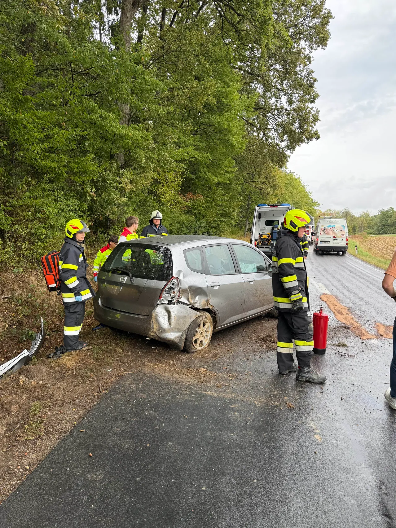Rettungskräfte kümmern sich um ein beschädigtes Auto am Straßenrand.