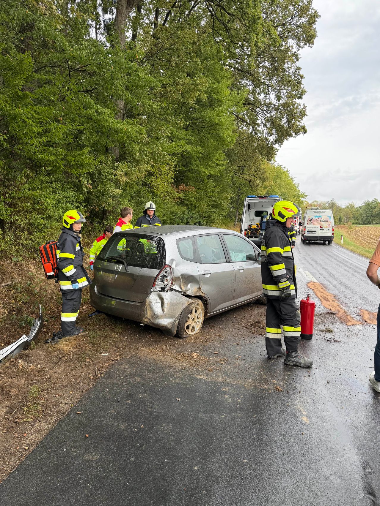 Rettungskräfte kümmern sich um ein beschädigtes Auto am Straßenrand.