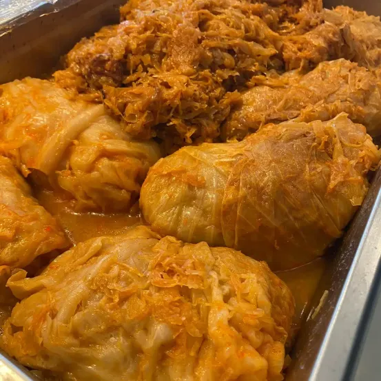 Nahaufnahme von Kohlrouladen gefüllt mit Fleisch und Reis, eingewickelt in Kohlblätter, in einer Metallschale mit goldbrauner Farbe.