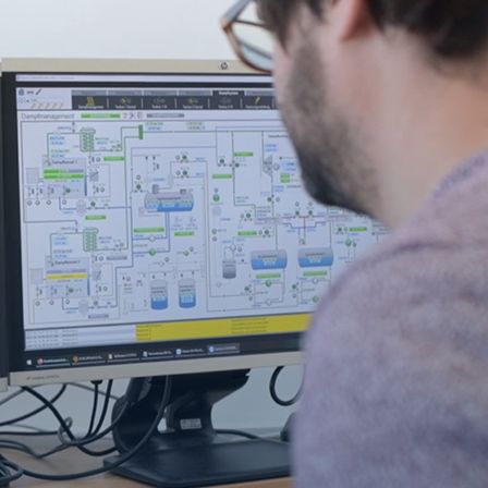 Ein Mann mit Brille schaut auf einen Computerbildschirm, der ein Systemdiagramm zeigt.