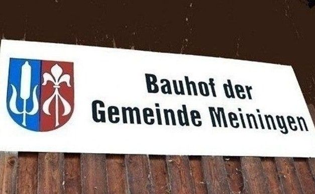 Ein Schild für die Gemeinde Meiningen. Es zeigt ein Logo mit einer stilisierten Blume und einem Wappenschild sowie den Text 'Bauhof der Gemeinde Meiningen'.