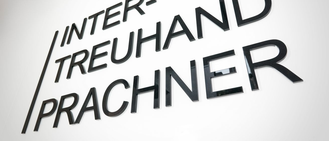 Das Schild zeigt in fetten, großgeschriebenen Buchstaben 'INTER-TREUHAND', wahrscheinlich der Name eines Unternehmens oder einer Organisation.