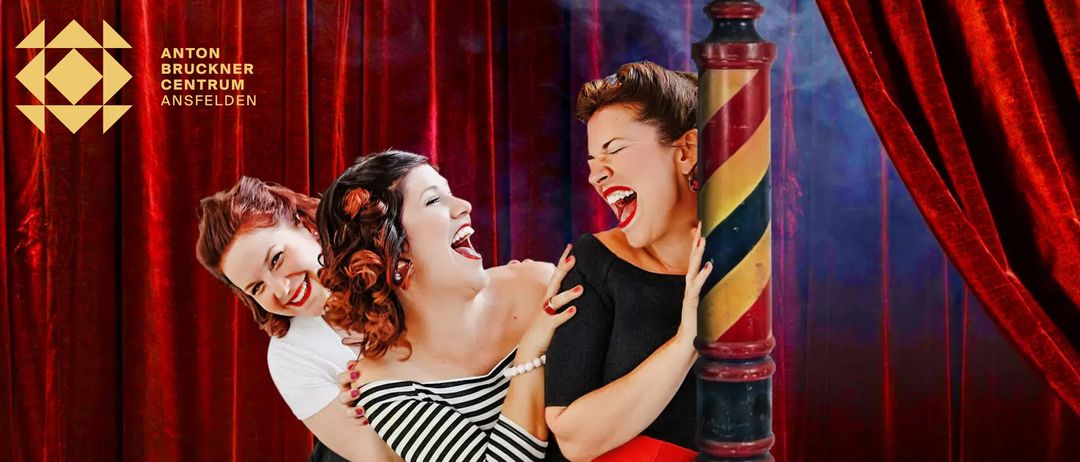 Drei Frauen lachen und umarmen sich in einer Vintage-Szene mit rotem Vorhang und gestreifter Stange. Sie tragen schwarze Kleider und scheinen eine gute Zeit zu haben.