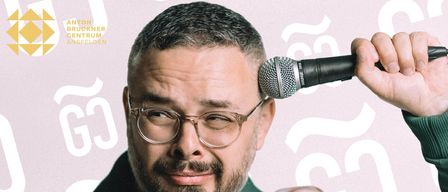 Ein Mann mit Brille und Bart lächelt in die Kamera. Er trägt ein grünes Poloshirt und hat ein Mikrofon auf dem Kopf.