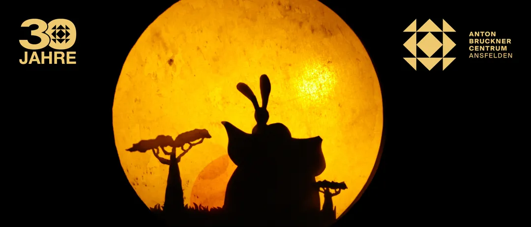 Eine Silhouette eines Elefanten mit einem Hasen auf dem Kopf steht vor einem gelben Hintergrund mit Bäumen.