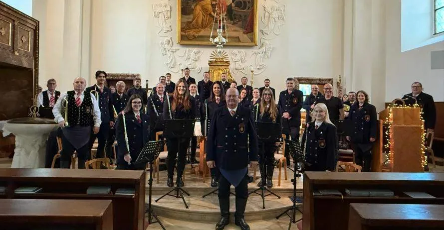 Ein Chor singt in einer Kirche mit einem großen Gemälde hinter ihnen.