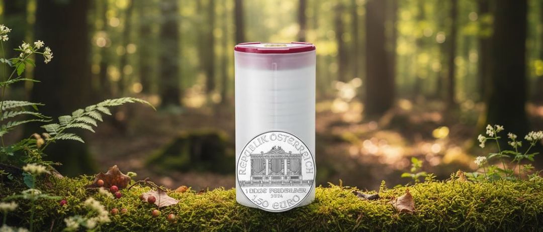 Ein weißer Plastikbecher mit rotem Deckel steht in einem Wald und zeigt eine 150-Euro-Münze mit einem Gebäudedesign.