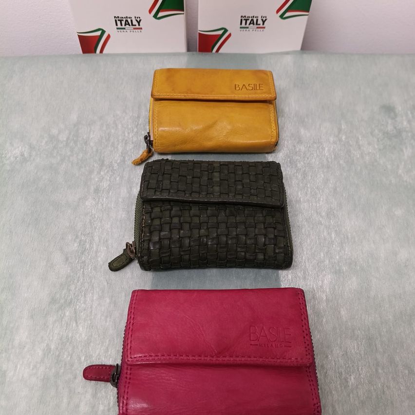 Drei Ledergeldbörsen auf einer grauen Oberfläche. Eine braune, eine schwarze und eine rote Geldbörse. Alle sind in Italien hergestellt.