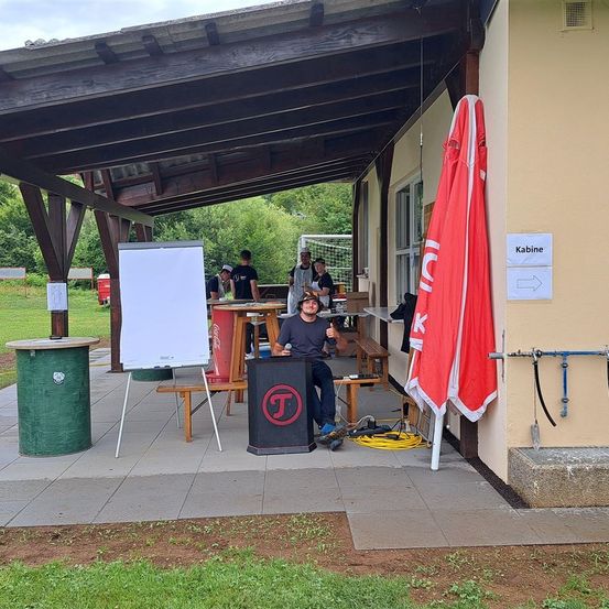 Bild enthält, Outdoors, Shelter, Person, Grass, Plant, Clothing, Hat, White Board, Shoe, Table