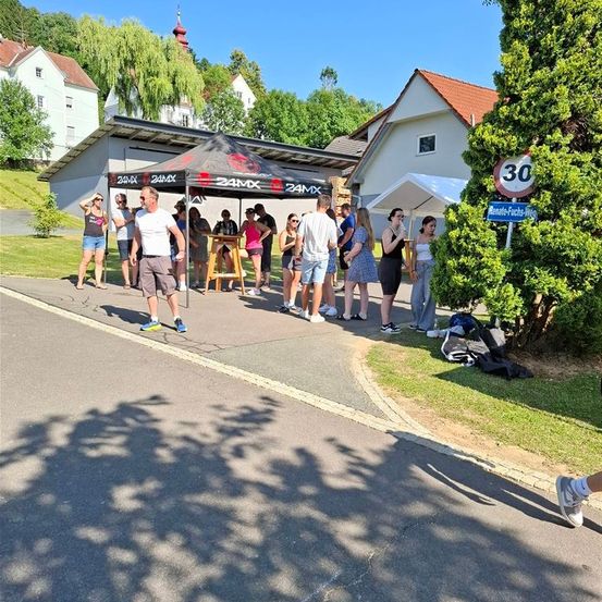 Eine Gruppe von Menschen steht in einer Reihe vor einem Zelt, wahrscheinlich bei einer Veranstaltung.