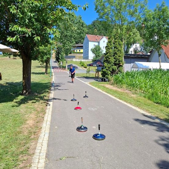 Ein Mann joggt auf einem Pfad mit mehreren farbigen Hütchen an der Seite, einem Zelt im Hintergrund und einigen Häusern.