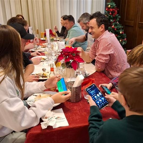 Eine Familie sitzt gemeinsam an einem festlich gedeckten Tisch mit Dekorationen und Feiertagsstimmung.
