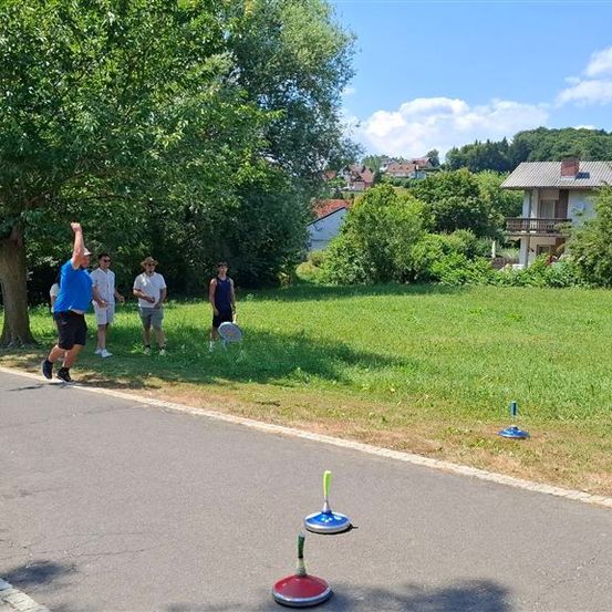 Eine Gruppe von Menschen spielt ein Spiel auf der Straße mit bunten Objekten. Eine Person wirft einen Frisbee.