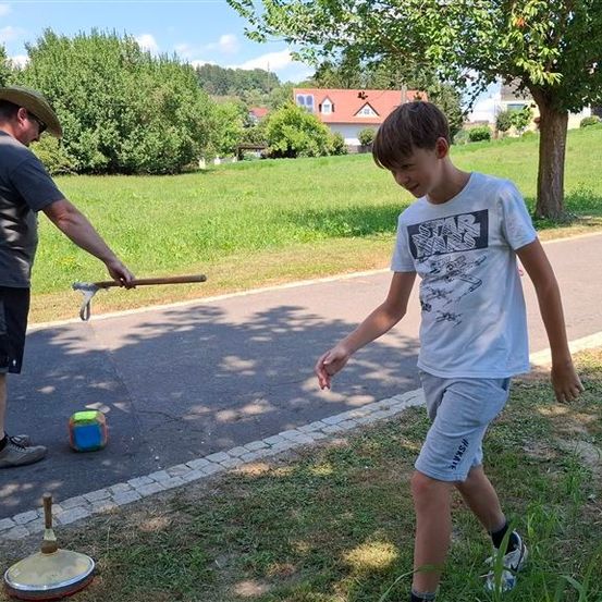 Ein Mann in einem Cowboyhut und ein Junge spielen mit einer Schleuder am Straßenrand.