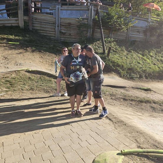 Ein Mann mit einer Kamera fotografiert zwei Männer vor einem staubigen Pfad.