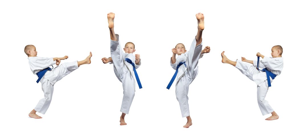 Ein junger Junge in einem Karate-Anzug führt einen hohen Kick mit beiden Beinen abgehoben vom Boden aus.