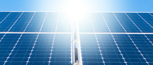 Ein Nahaufnahme von Solarmodulen, die der hellen Sonne mit einem blauen Himmel im Hintergrund zugewandt sind.