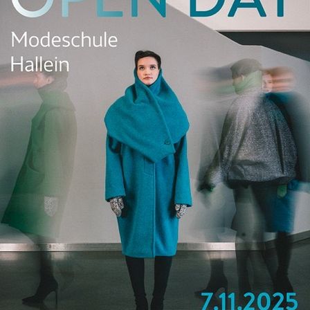 Tag der offenen Tür an der Modeschule in Hallein. Eine Frau in einem blauen Mantel steht vor einer weißen Wand mit einem Schild. Dahinter sind zwei weitere Personen verschwommen. Datum und Uhrzeit sind angezeigt.
