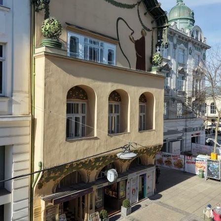 Eine Stadtlandschaft mit architektonischen Gebäuden, einer Uhr und Menschen, die auf der Straße spazieren.