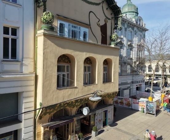 Eine Stadtlandschaft mit architektonischen Gebäuden, einer Uhr und Menschen, die auf der Straße spazieren.
