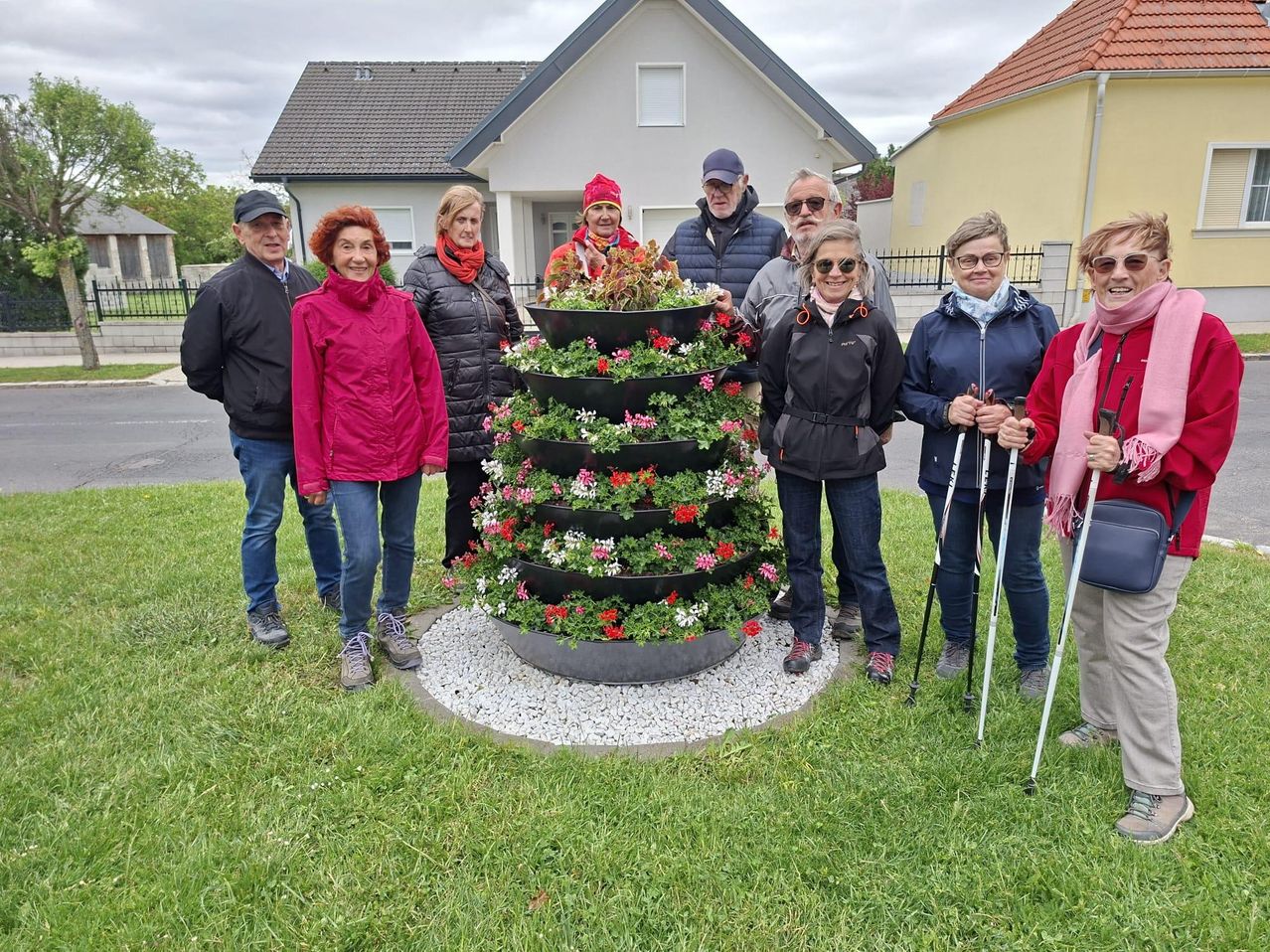 Eine Gruppe von Menschen posiert für ein Foto mit einer Blumenarrangement vor einem Haus.