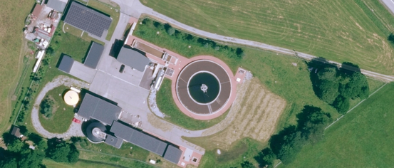 Eine Luftaufnahme einer Anlage mit Solarpanelen, einem runden Wassertank und einem großen Feld.