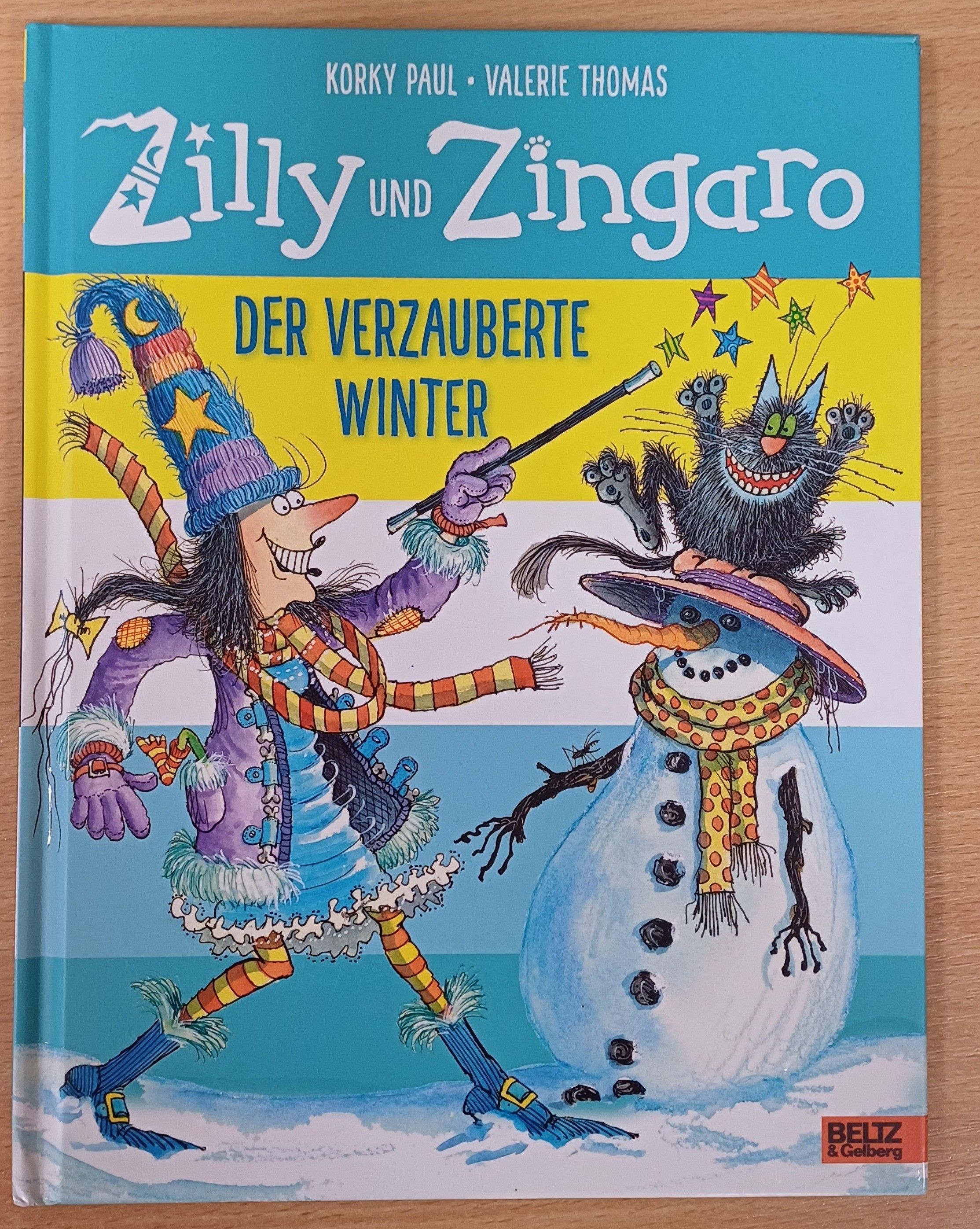Buchcover von 'Zilly und Zingaro: Der Verzauberte Winter' mit einer Hexe und einem Schneemann.