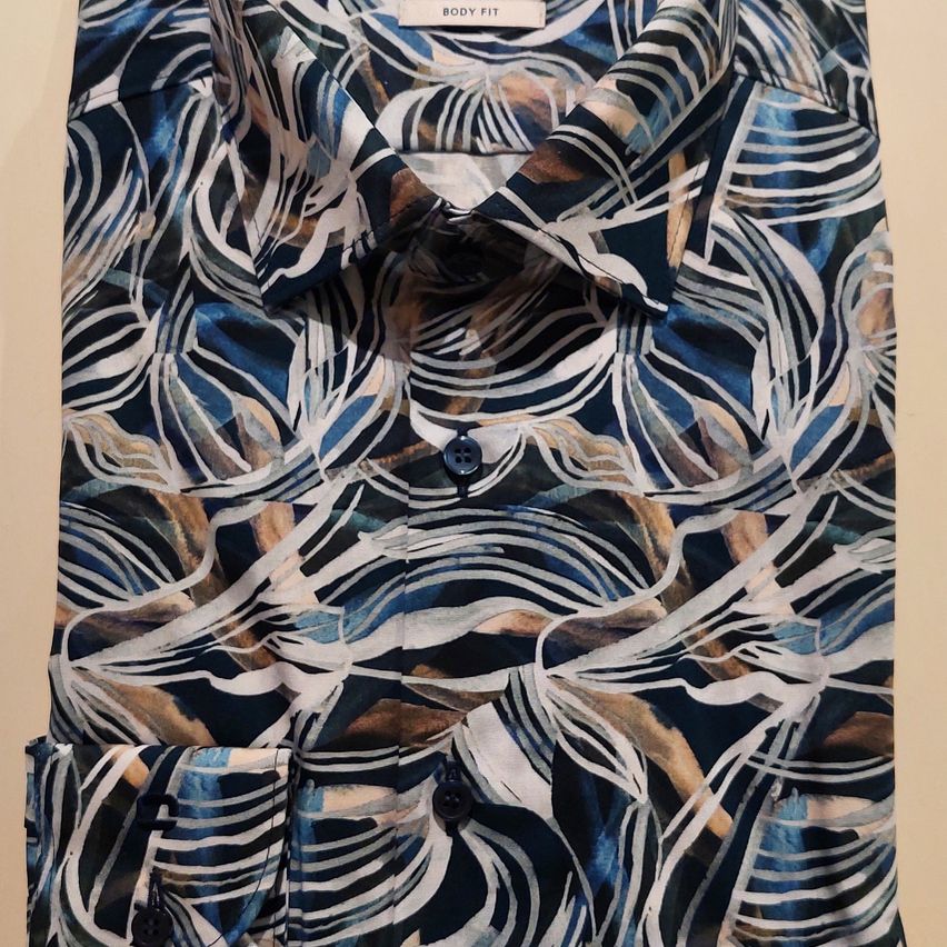 Ein Nahaufnahme eines Body Fit Hemdes mit einem blauen und weißen abstrakten Blattmuster. Das Hemd wird auf einem weißen Hintergrund präsentiert.