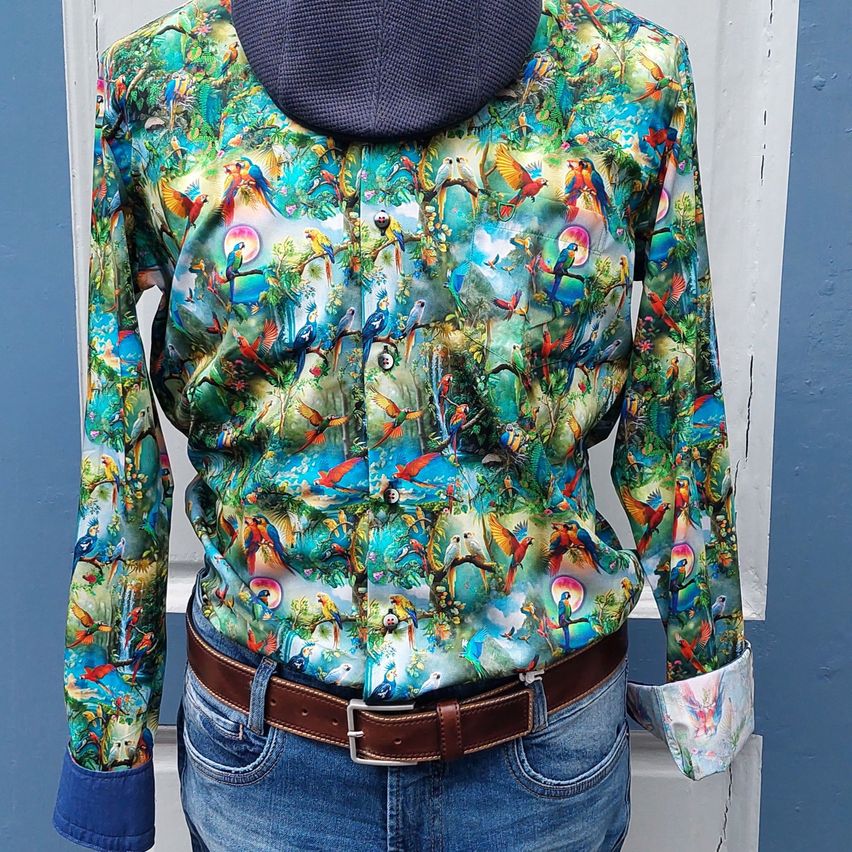 A colorful long-sleeved shirt with a parrot print design, paired with a brown belt and blue jeans.
