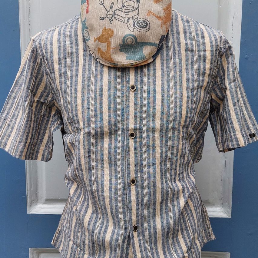 Ein gestreiftes Hemd mit einem Cartoon-Zeichenbandana auf einem Mannequin. Das Hemd ist blau und beige.
