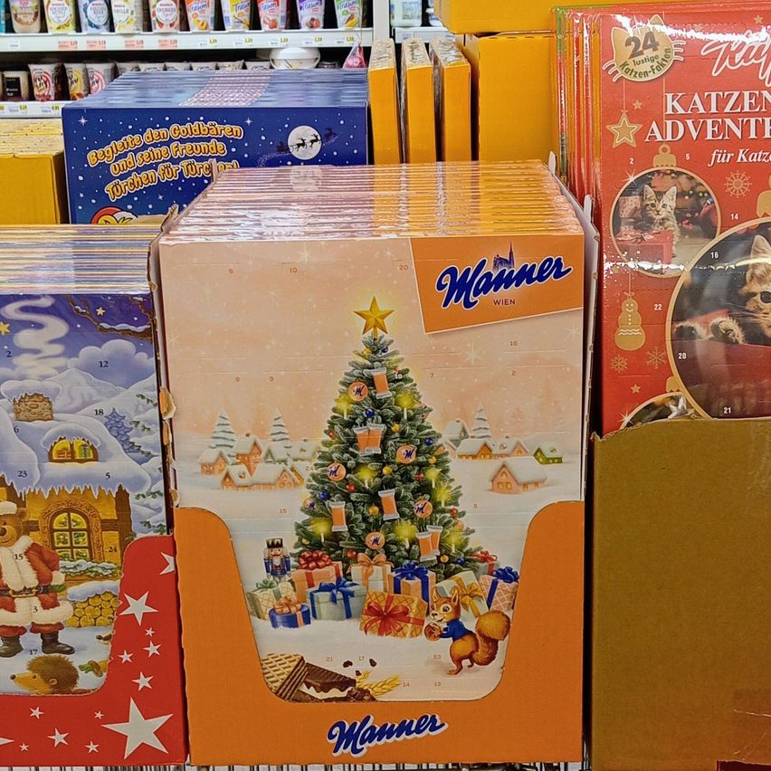 Eine Ausstellung von Weihnachtsdekorationen in einem Geschäft, mit einem Stapel von Schachteln mit einem Weihnachtsbaumdesign, begleitet von anderen Produkten im Hintergrund.