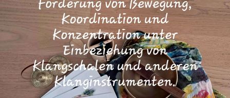 Ein Bild von Lernmaterialien für Kinder, einschließlich eines Buches, Karten und Musikinstrumenten wie Gongs und einem Xylophon, auf einer Holzoberfläche mit Text über Bewegung und Konzentration.