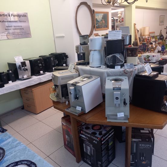 Ein Geschäft mit verschiedenen Kaffeemaschinen zur Ausstellung, darunter eine weiße und silberne Maschine im Vordergrund.