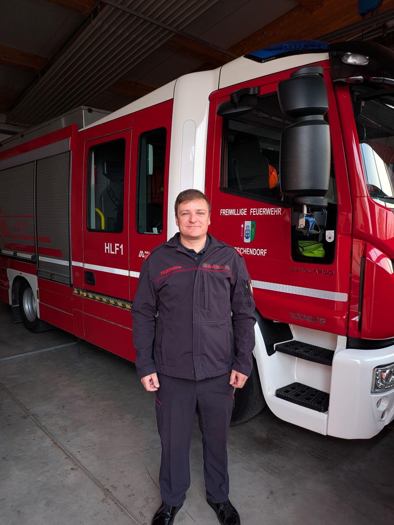 Ein Mann in Uniform steht vor einem Feuerwehrauto mit der Aufschrift Freiwillige Feuerwehr.