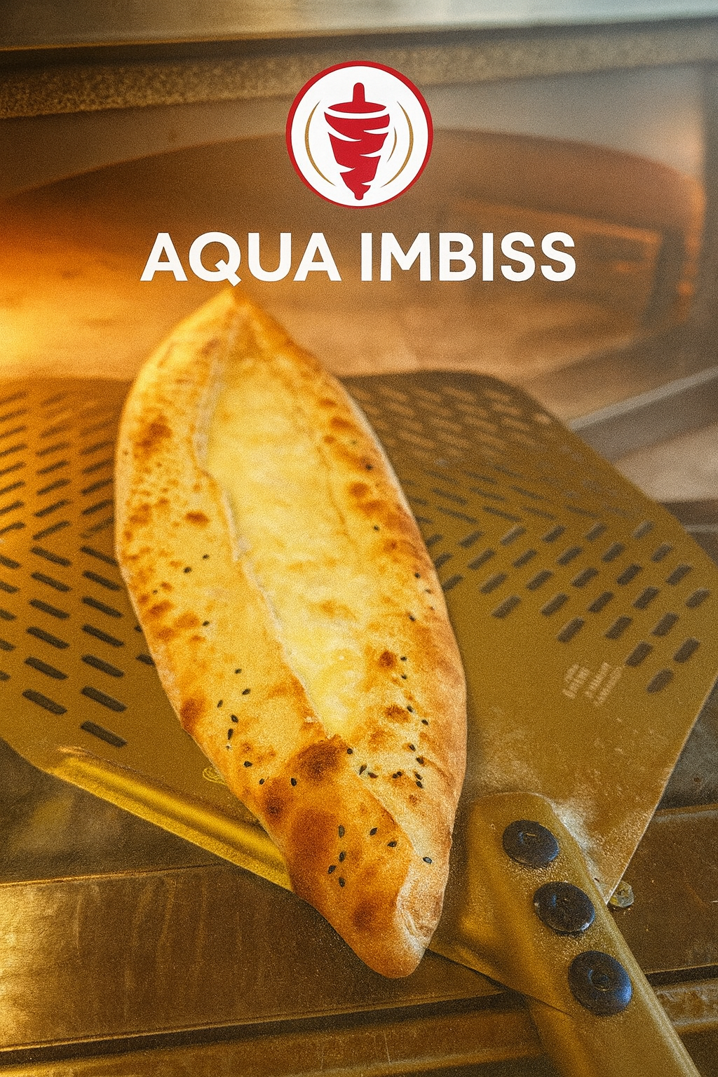 Eine Nahaufnahme eines gebackenen Fladenbrots mit Sesamkörnern auf einem Spatel, die Worte Aqua Imbiss in der oberen linken Ecke und ein unscharfer Ofen im Hintergrund.