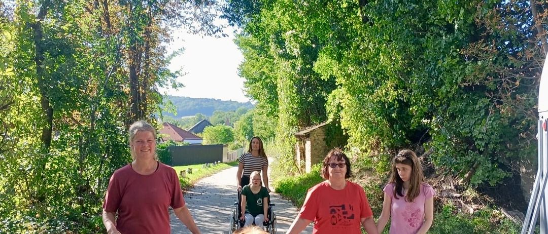 Eine Familie führt ein kleines Pferd auf einem Pfad, hinter ihnen eine Frau im Rollstuhl.