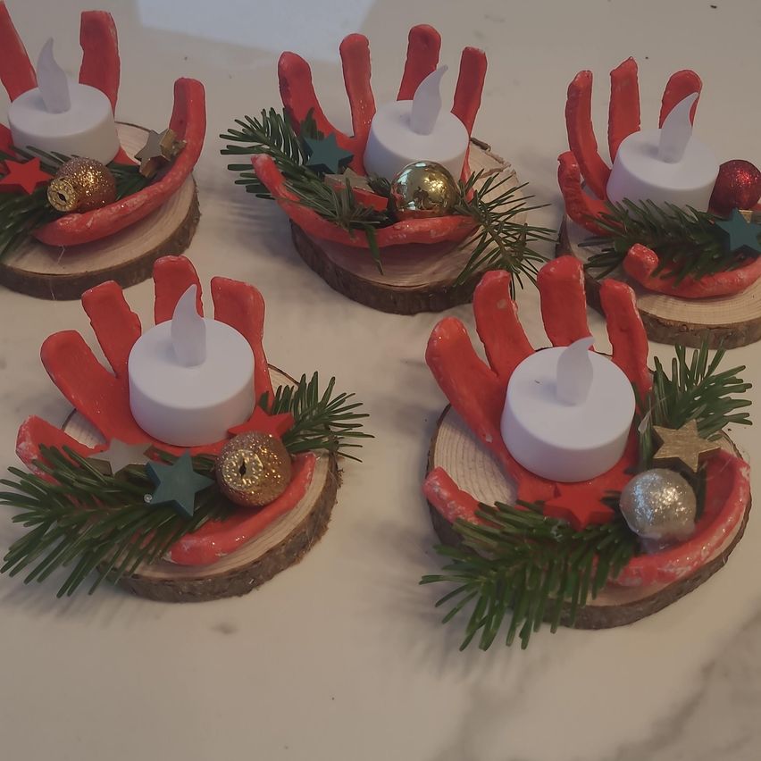 Fünf festliche Kerzenhalter aus Holz mit roten handartigen Formen, jeder mit einer weißen Kerze und Weihnachtsdekoration. Die Kerzen sind nicht angezündet.
