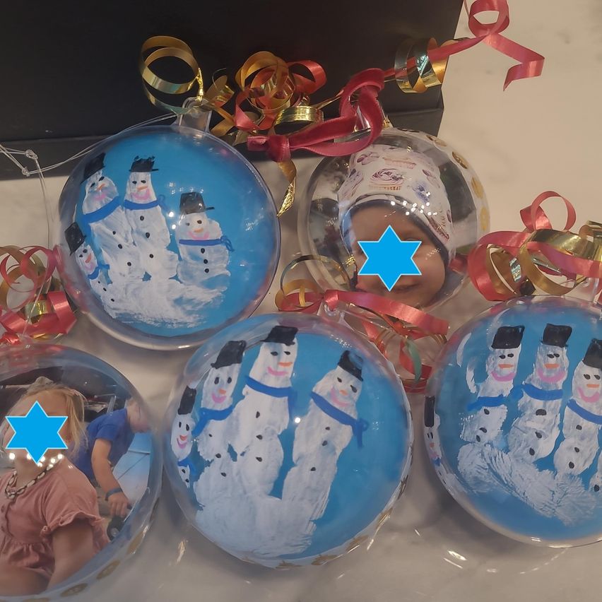 Eine Sammlung von bunten Weihnachtskugeln mit Schneemann-Designs und blauem Hintergrund. Jede Kugel hat ein Sternensymbol darauf. Einige Kugeln haben gedruckte Bilder von Kindern.