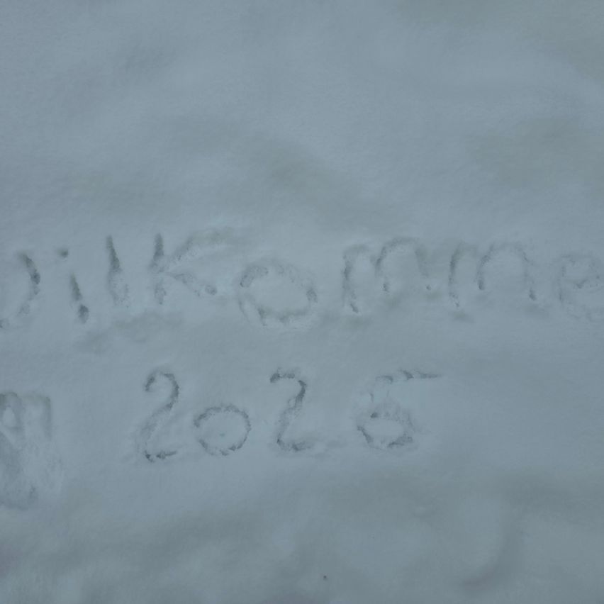 Schneebedeckte Oberfläche mit dem Text 'Willkommen 2026' darauf geschrieben.