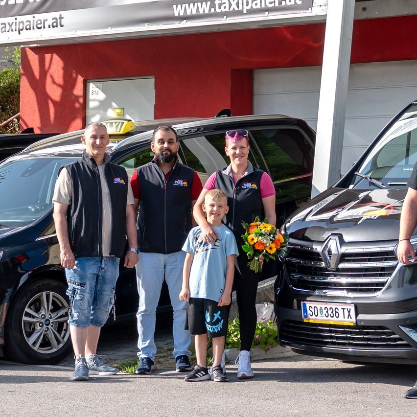 Eine Gruppe von Menschen steht vor einem Taxiunternehmen mit einem Renault-Taxi im Vordergrund.