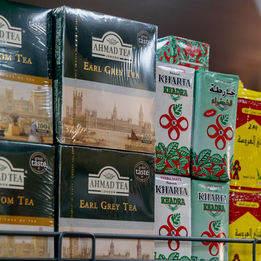 Stacks of Ahmad Tea and Kharta tea boxes are displayed on a shelf, with a variety of tea types and packaging designs.