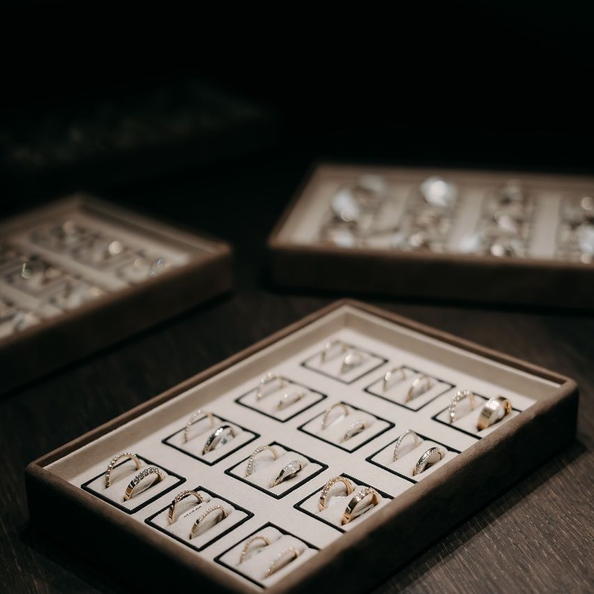 Drei Schmuckkästchen auf einem Holztisch enthalten verschiedene Ringe, einschließlich Gold und Silber. Die oberste Schachtel ist leicht verschwommen.