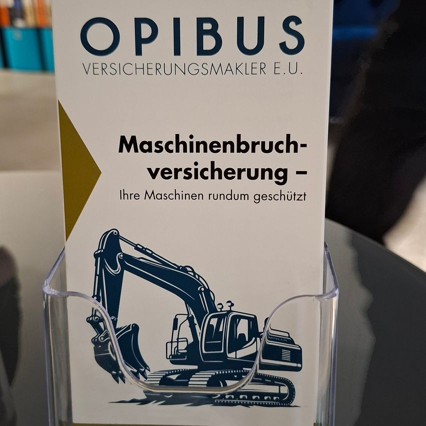 A brochure titled 'Maschinenbruch-versicherung' by OPIBUS Versicherungsmakler E.U. is displayed in a clear holder, showing a stylized excavator in blue.