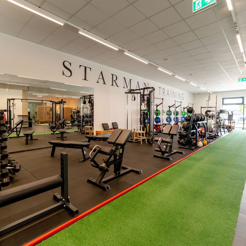 A well-equipped gym with various exercise machines and weights, labeled 'Starman Training' on the wall.