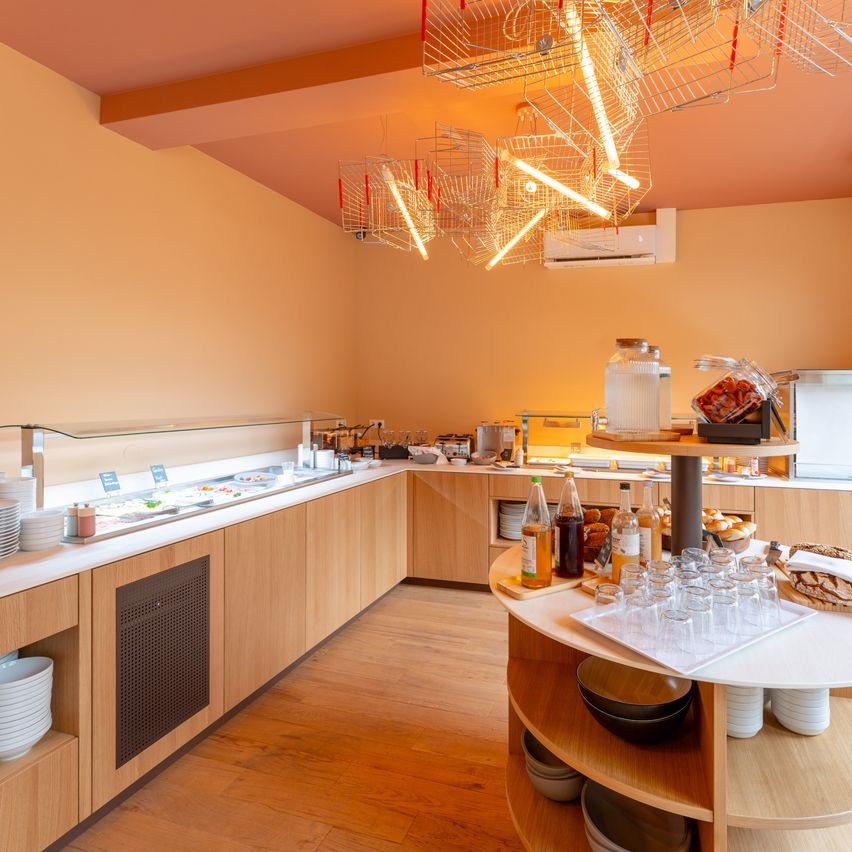 Ein modernes, gut beleuchtetes Restaurant mit Holztheken, einer Glasvitrine und einem runden Tisch mit verschiedenen Lebensmitteln und Gläsern.