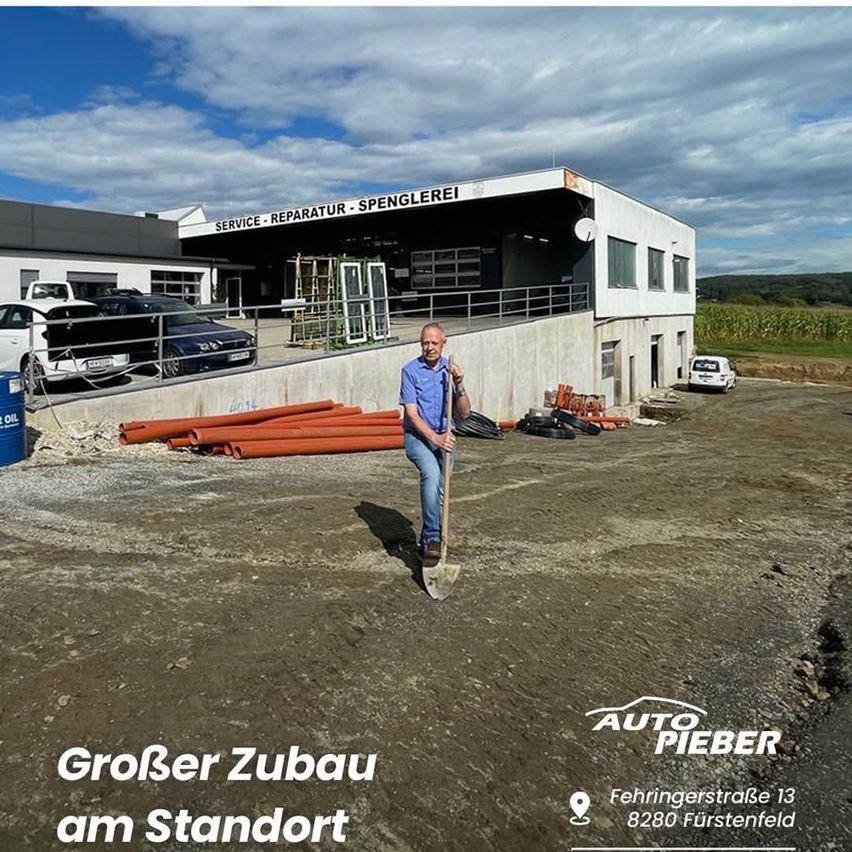 An adult man holding a shovel stands in front of a building with the words 'Service Reparatur Spengerei' on top. Cars are parked in front. A sign reads 'Grosser Umbau am Standort'.