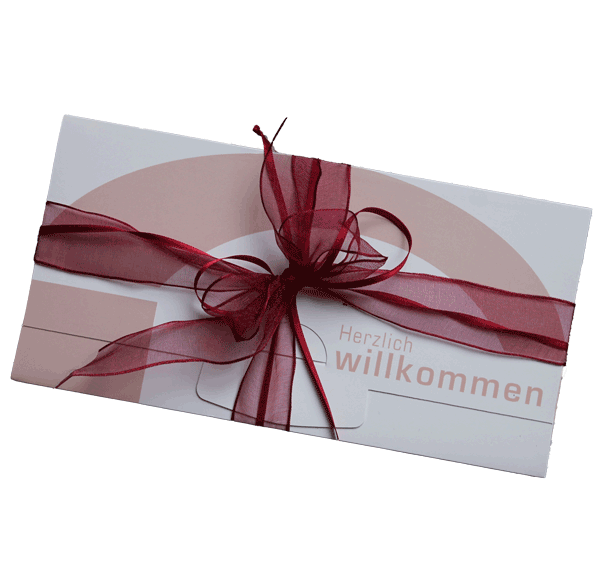 Eine weiße Karte mit einem roten Band und einer Botschaft, die 'Herzlich willkommen' in einer stilisierten Schrift sagt, wahrscheinlich zur Begrüßung von jemandem gedacht.