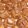 Eine Nahaufnahme mehrerer ganzer Laibe von braunem Brot mit einer knusprigen Kruste und einigen Scheiben darauf.